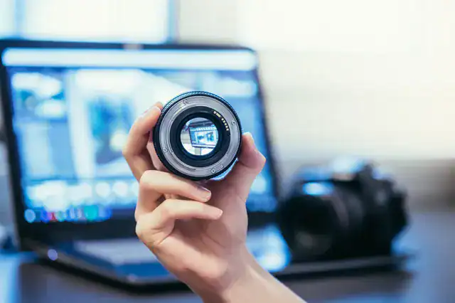 photographer holding lens camera laptiop